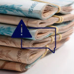 Bolos de notas de 100 e 50 reais e um quadro em png azul com símbolo que representa atenção