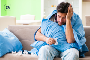 Homem doente coberto com cobertor azul abraçando travesseiro, segurando lenço de papel