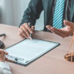 Advogado explicando contrato para cliente, com balança da justiça e martelo